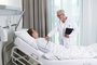 Arzt bei der Visite im Patientenzimmer eines modernen Krankenhauses