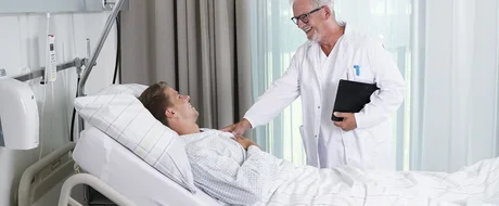 Arzt bei der Visite im Patientenzimmer eines modernen Krankenhauses