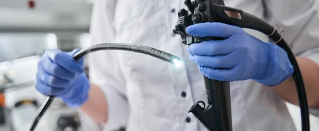 Eine Person hält ein Endoskopiegerät in einer medizinischen Einrichtung in den Händen