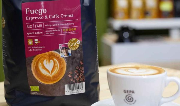 PEG - Kaffee Fuego von GEPA Eine Tasse Cappuchino, neben dieser steht eine Kaffeeverpackung von GEPO.